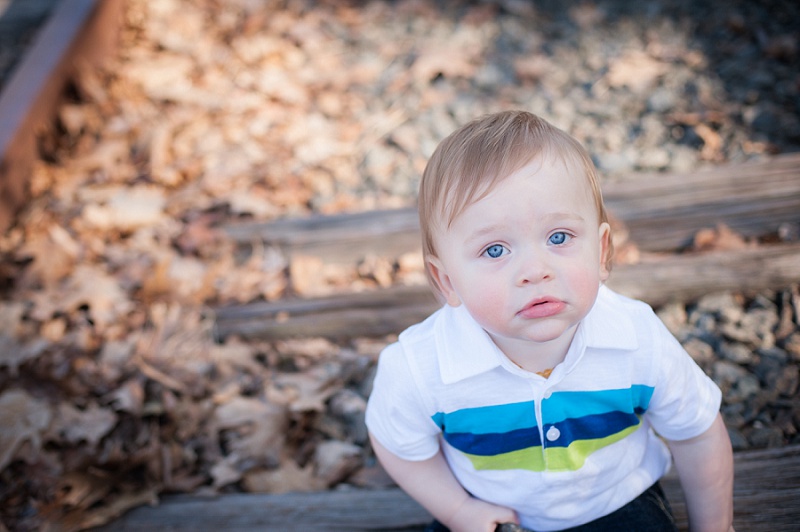 Blue eyed boy sitting on train tracks looking up