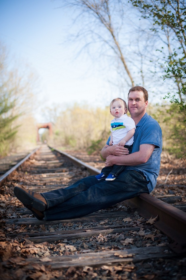 Father holding son sitting on train tracks