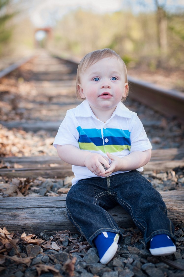 Blue eyed boy sitting on train tracks