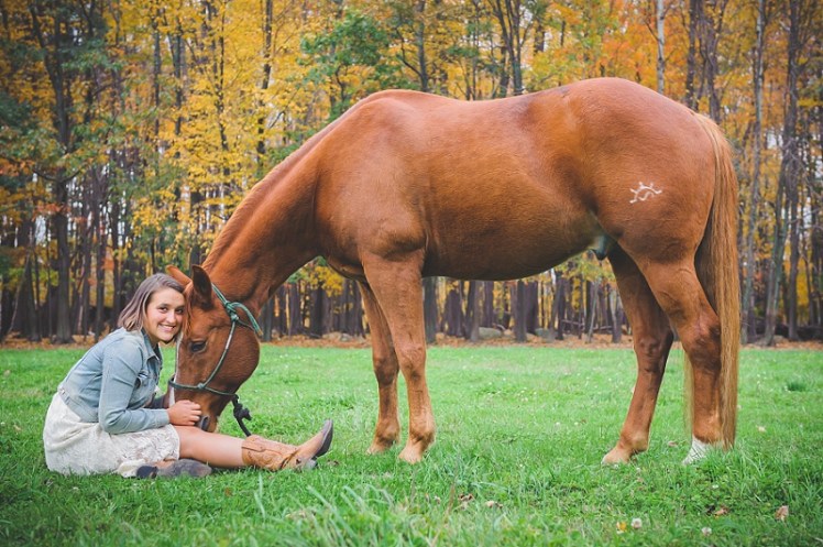 Girl sitting down with horse's head in her lap