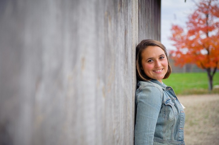 Senior portrait girl leaning against a barn