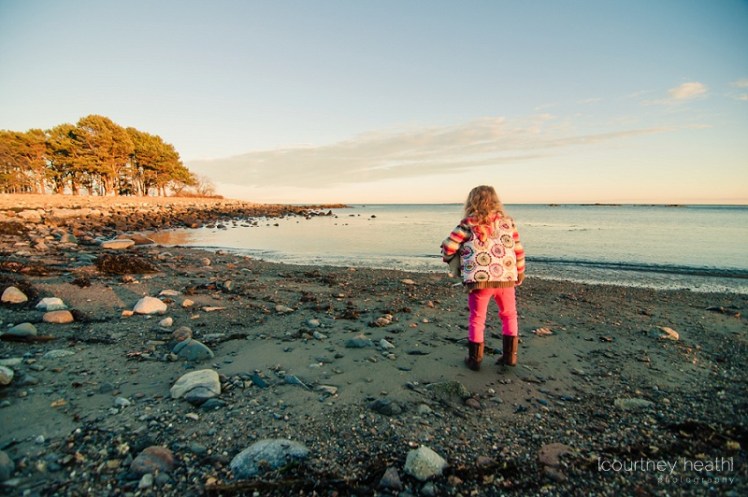 Young girl standing next to ocean water