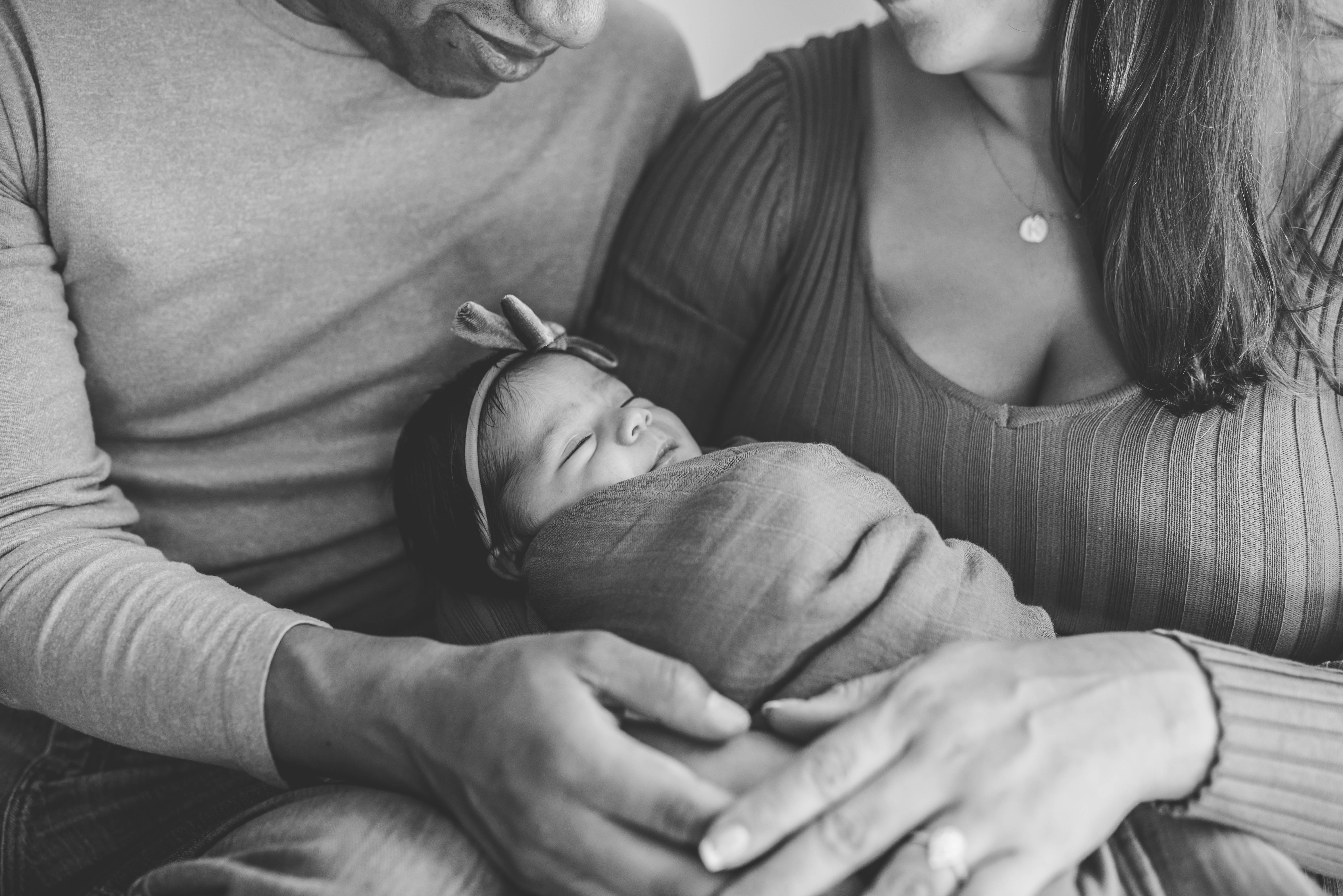 black and white image of new parents holding baby girl in swaddle in New Hampshire